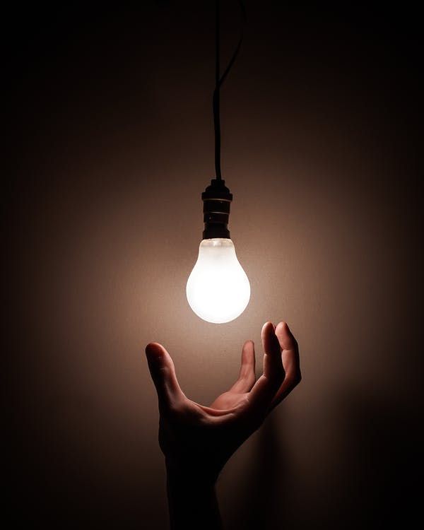 Photo of a hand reaching for a light bulb